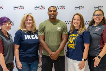 Teachers posing in front of WPS backdrop